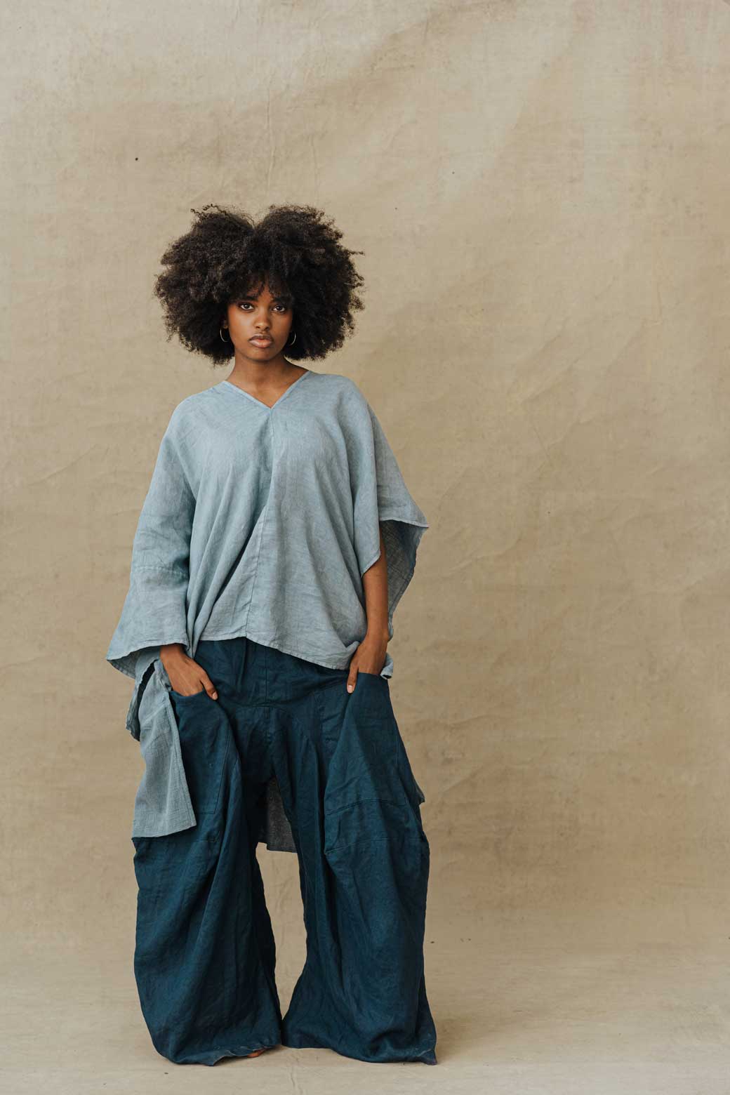 A person standing wearing a blue linen oversized shirt and matching skirt with a flowered pattern. The shirt has a pointelle texture and the skirt has a wide flare.