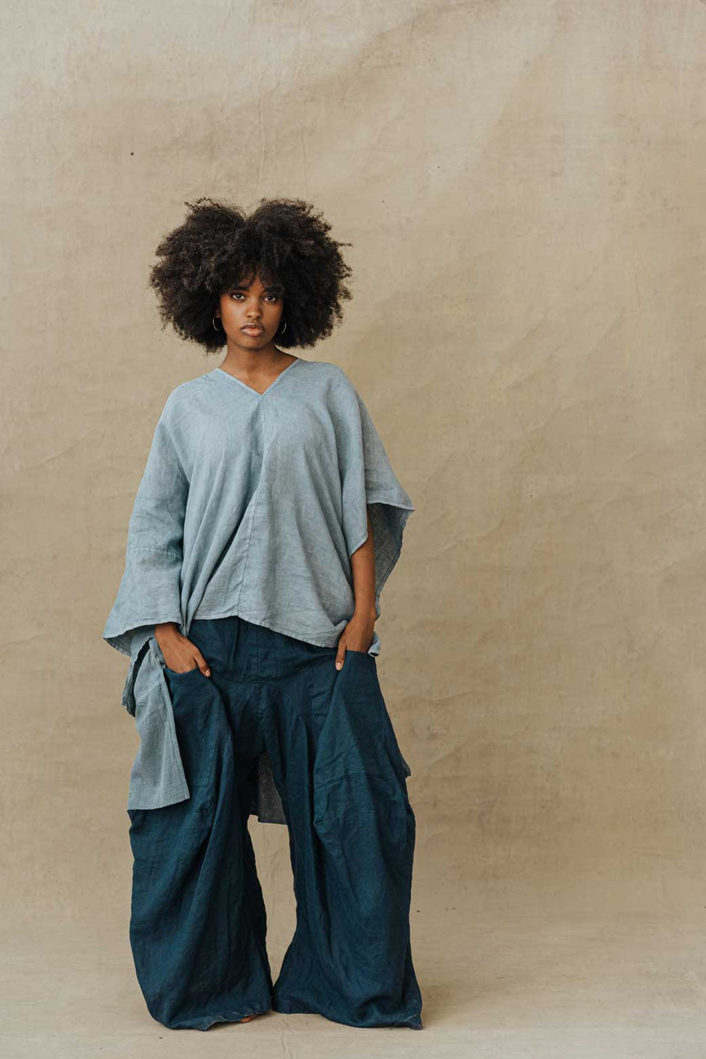 A person standing wearing a blue linen oversized shirt and matching skirt with a flowered pattern. The shirt has a pointelle texture and the skirt has a wide flare.